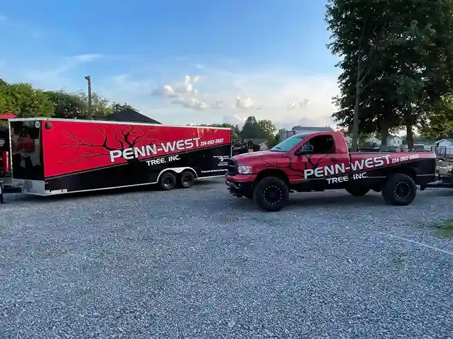 Penn West Tree Inc branded red pickup truck and equipment trailer parked in Hermitage, PA