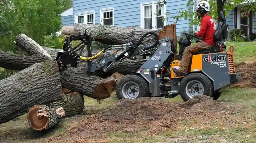 Mini loader clearing cut logs and brush from a lot in Hermitage, PA